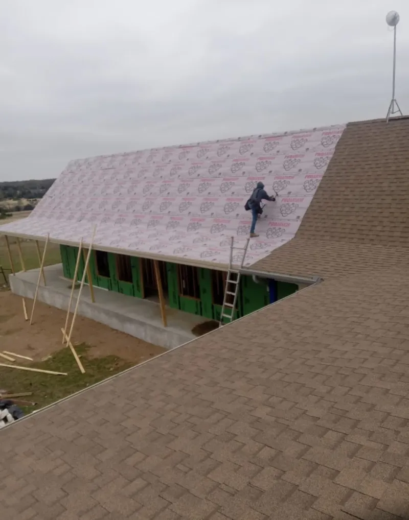 Worker preparing underlayment for a metal roof installation in Scituate